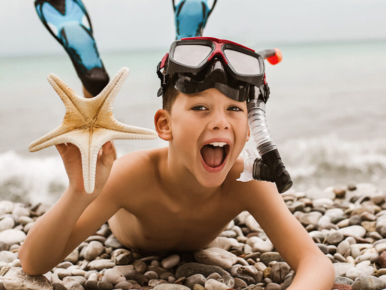 Junge mit Flossen am Meer, Ferien